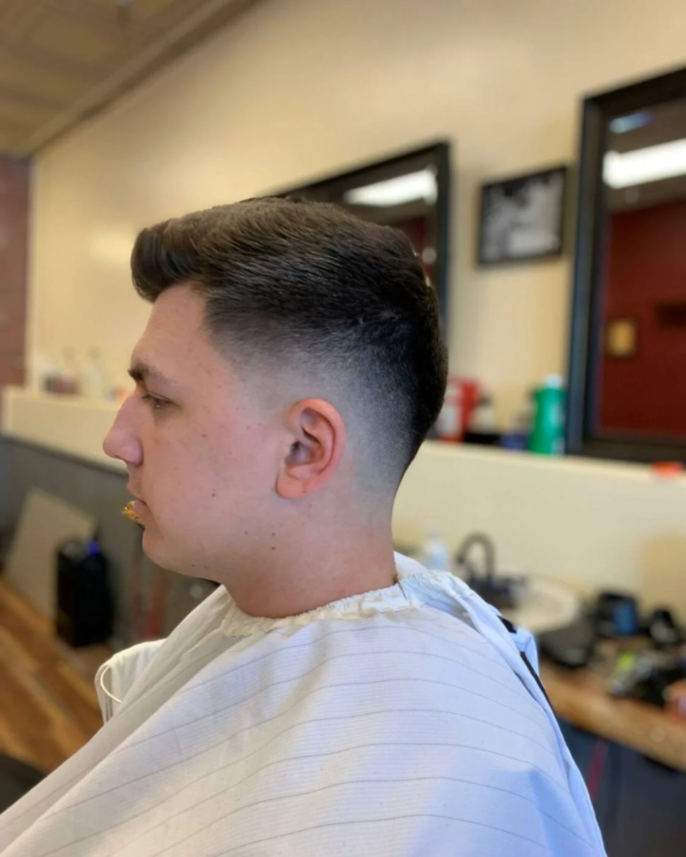 Low skin fade with a swept-back top, side profile in the chair at Chico's